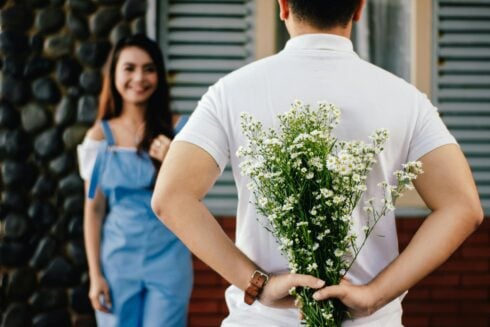 Man with flowers in front of a woman.